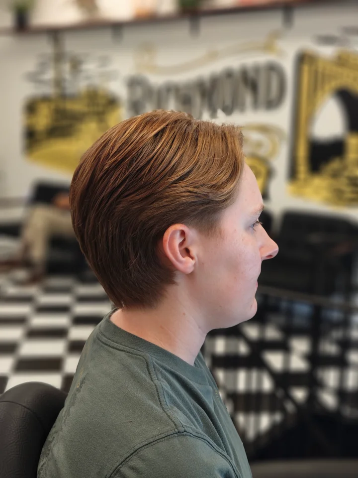 Long copper-colored hair swept back in layers at Richmond Barbershop